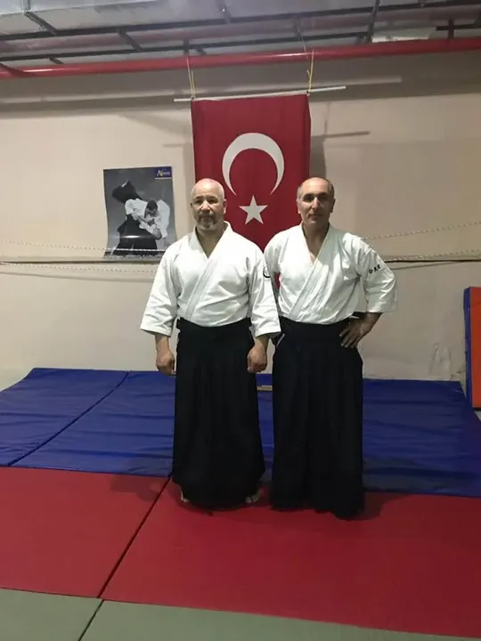 Salonda bayrak önünde iki aikido eğitmeni